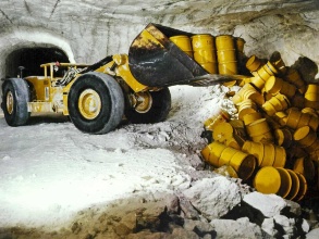 Im Atommülllager Asse schiebt ein Bagger mit seiner Schaufel Fässer mit radioaktivem Müll in eine Salzgrube.